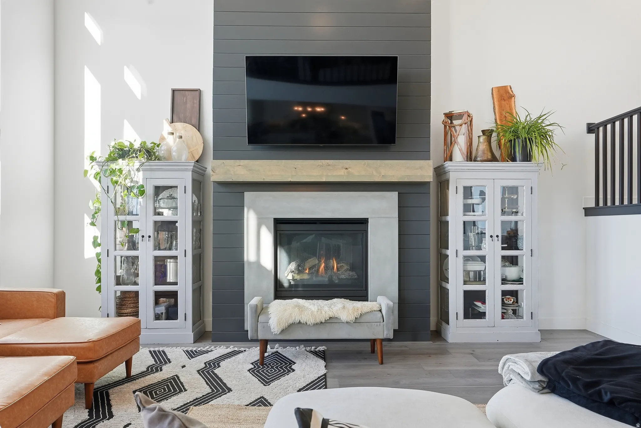 Living area featuring a modern fireplace with a light-toned surround and dark shiplap accent wall