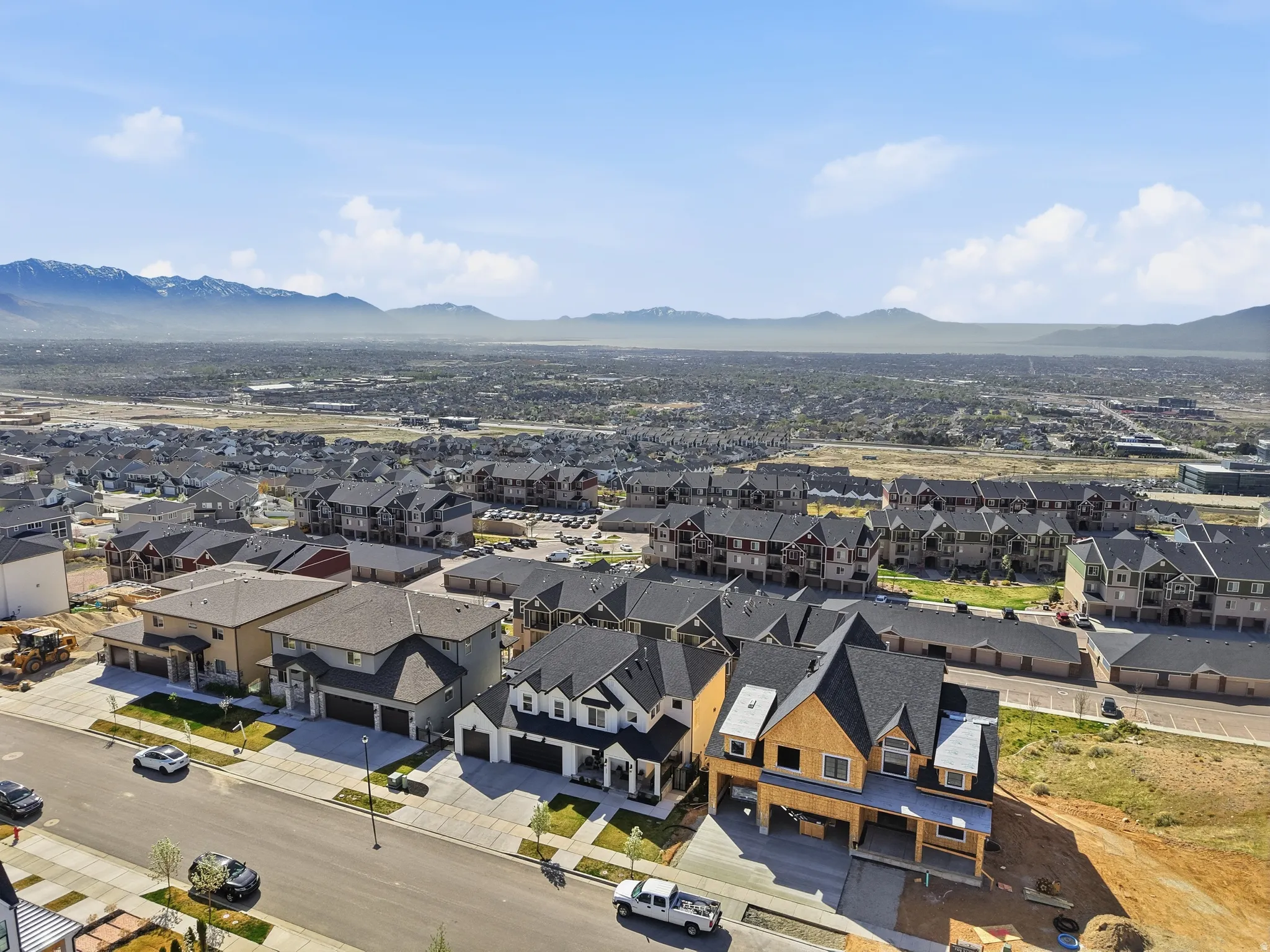 Expansive residential development featuring a diverse range of single-family homes and multi-story buildings, surrounded by a mountain backdrop