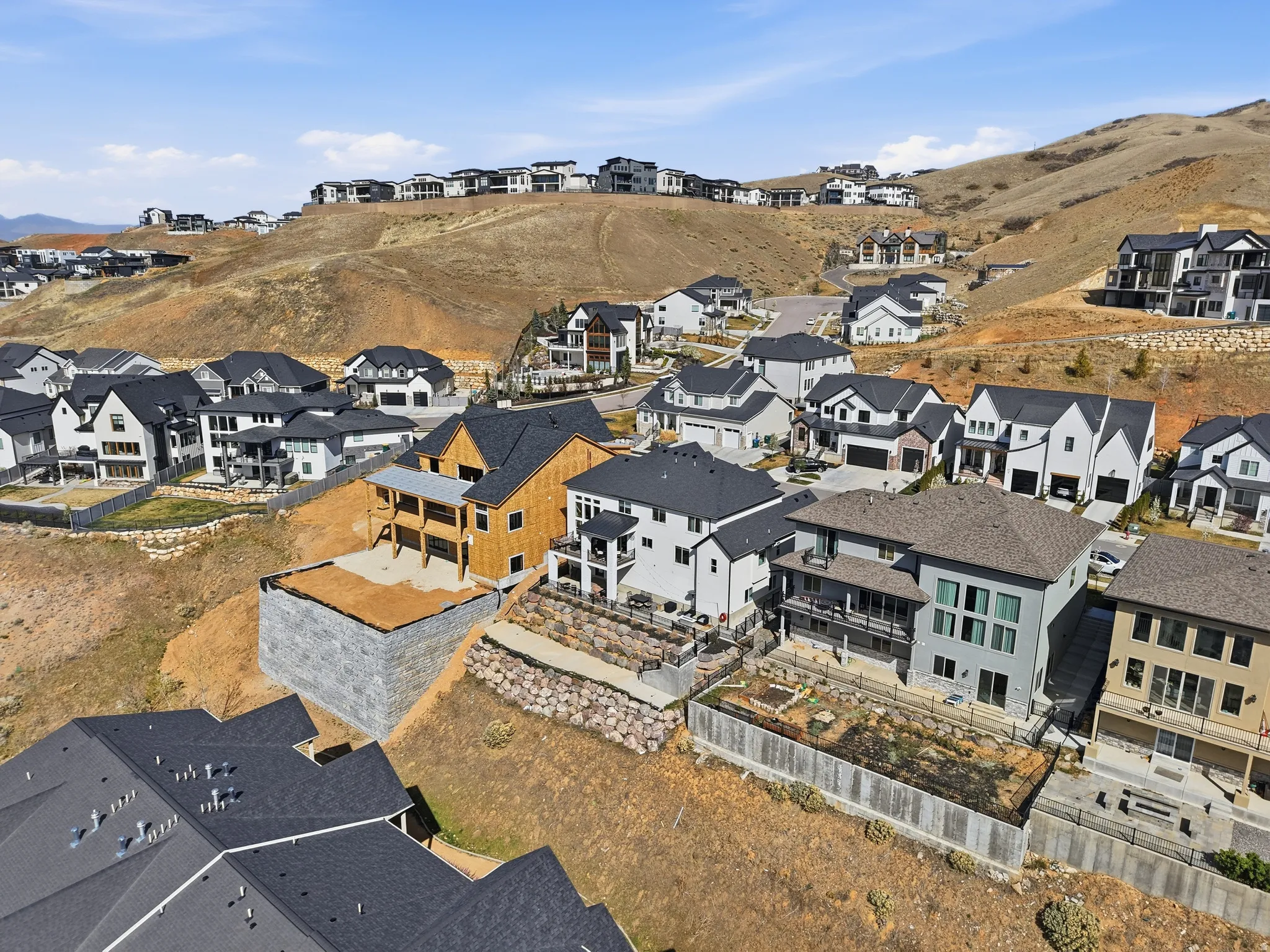 New construction property featuring a large retaining wall, a multi-level deck, and a partially framed second story
