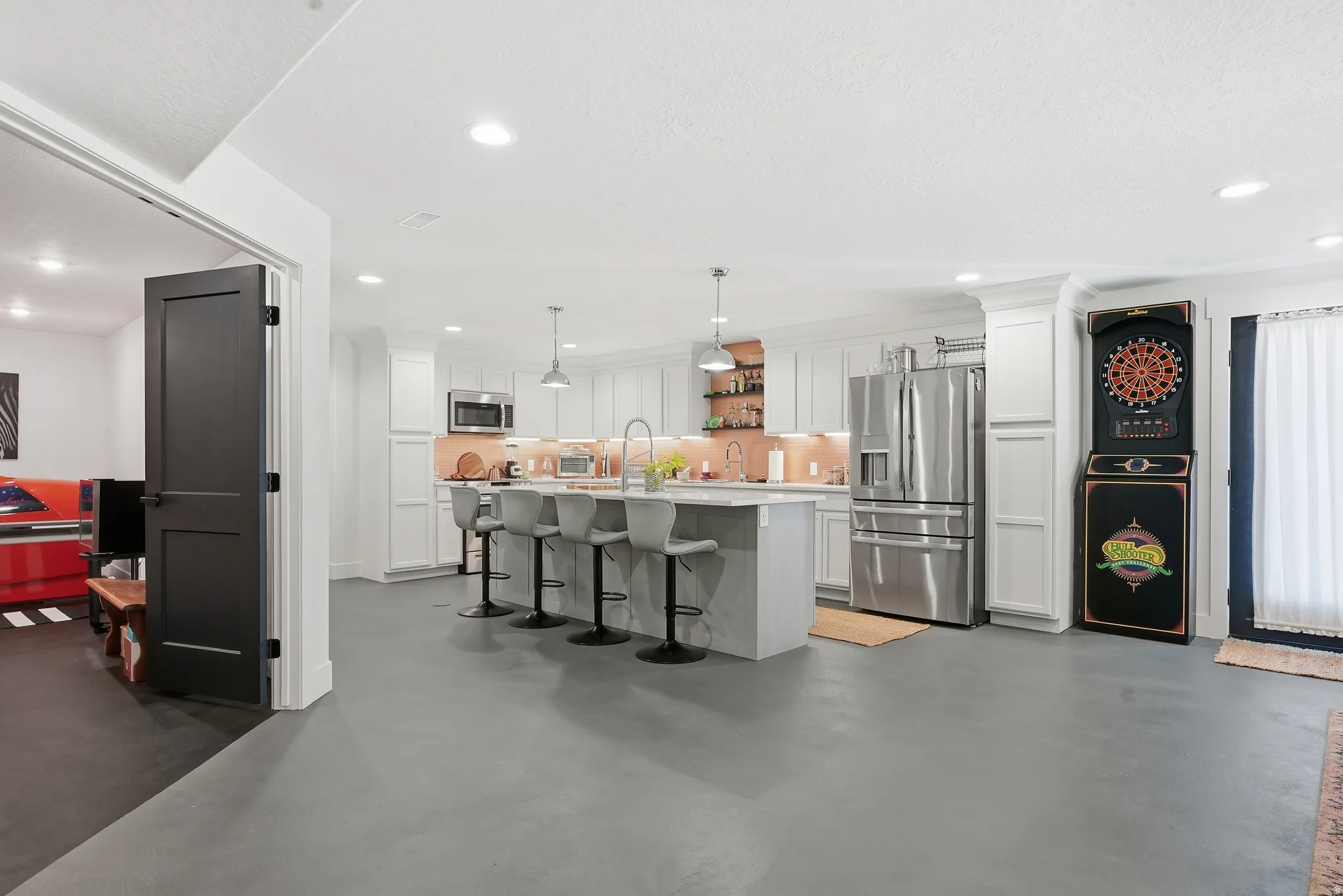 Open-concept kitchen featuring white cabinetry, stainless steel appliances, a center island with seating, and recessed lighting