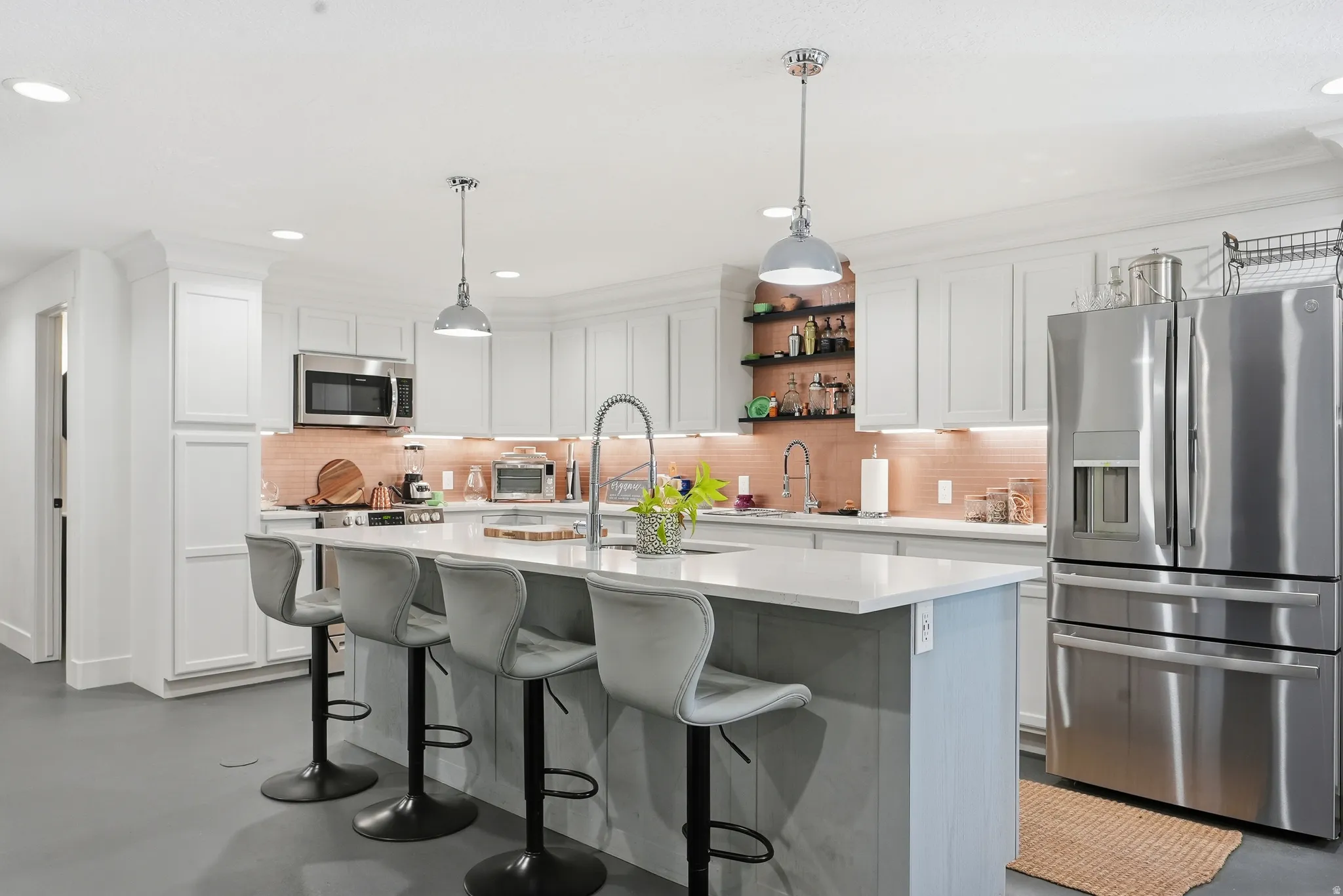 Kitchen featuring a central island with countertop seating, white shaker cabinetry, stainless steel appliances, and a tiled backsplash