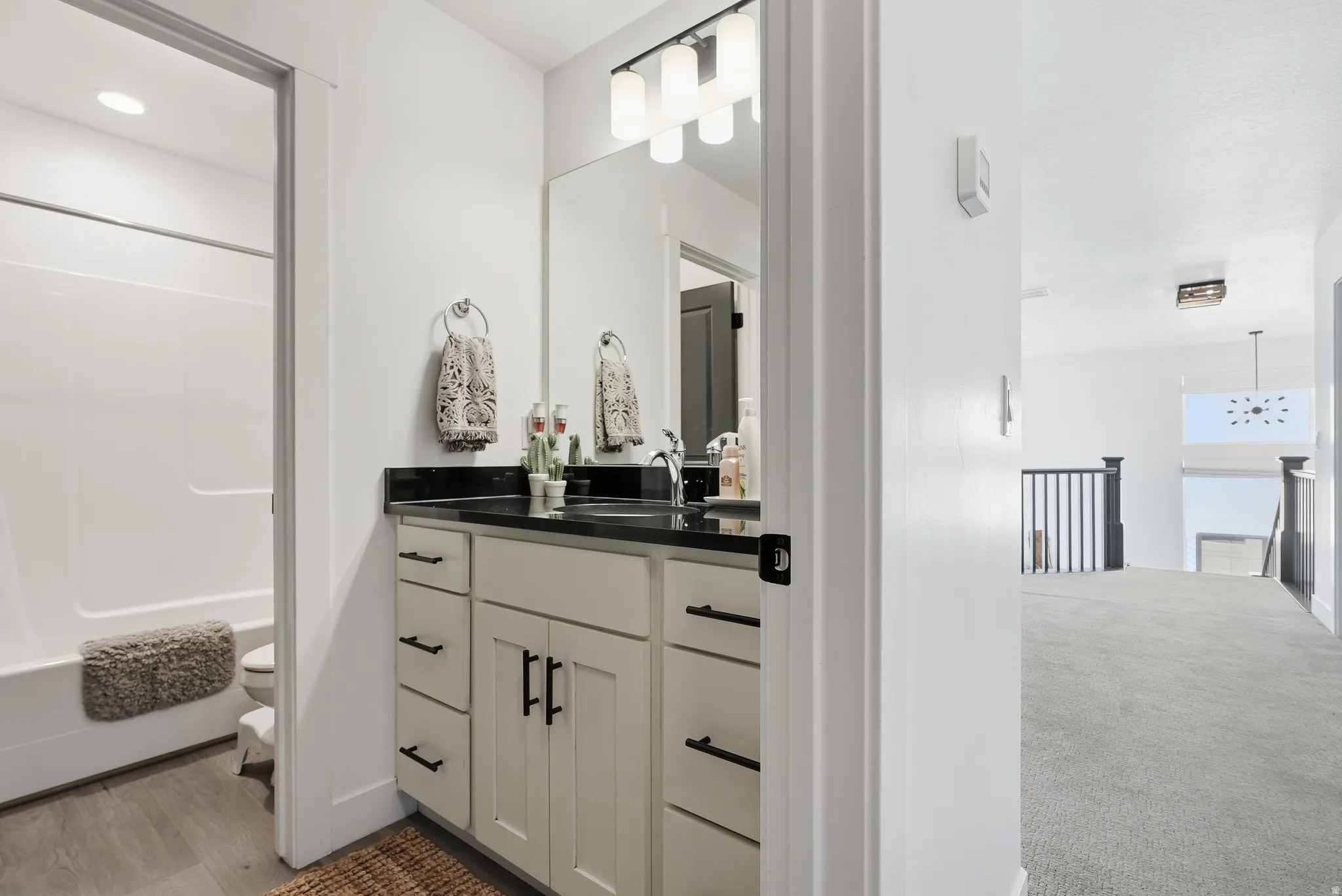 Bathroom vanity featuring a dark countertop, undermount sink, and light cabinetry with matte black hardware