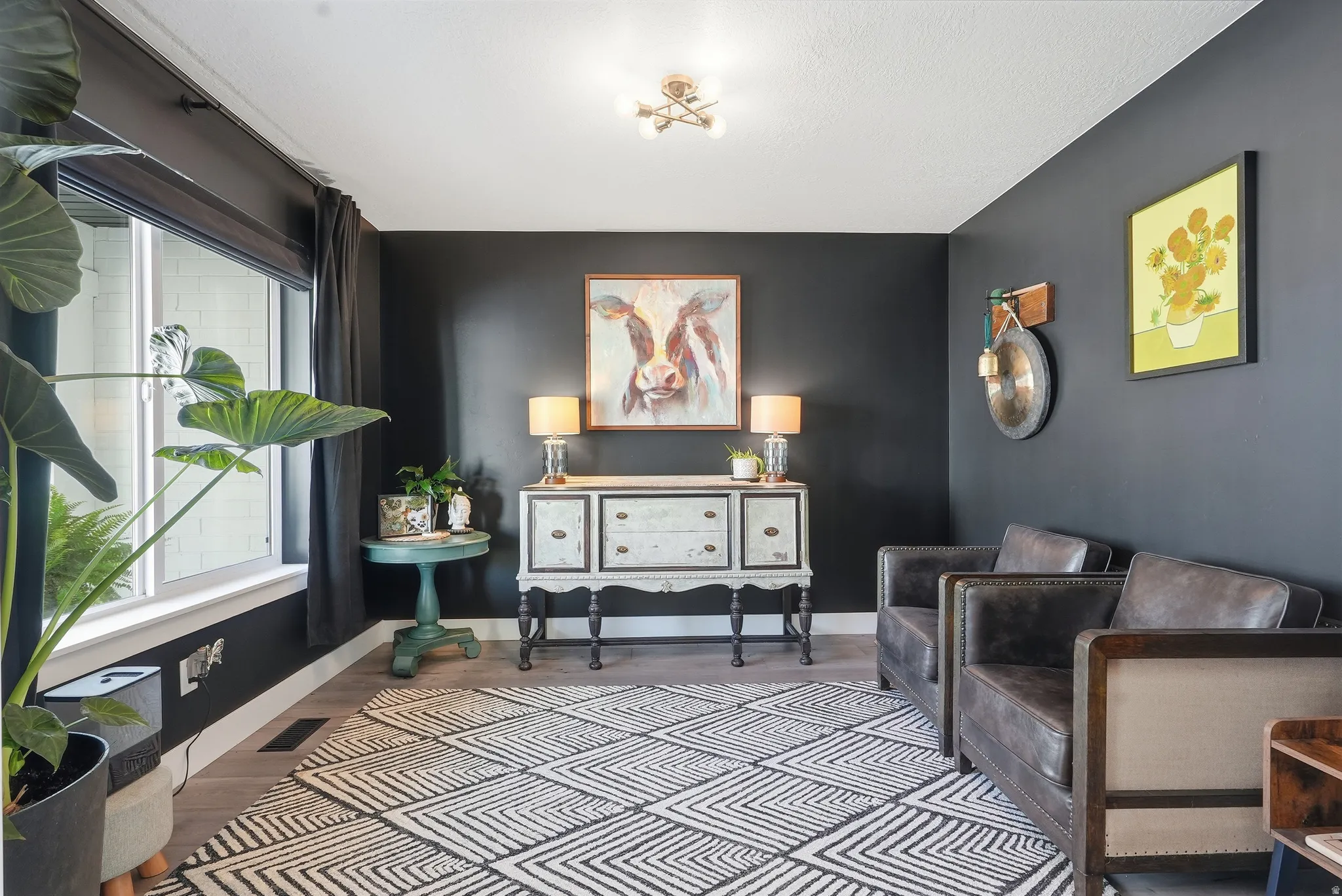 Spacious room featuring dark-painted walls, wood-finish flooring, and a large window with white trim