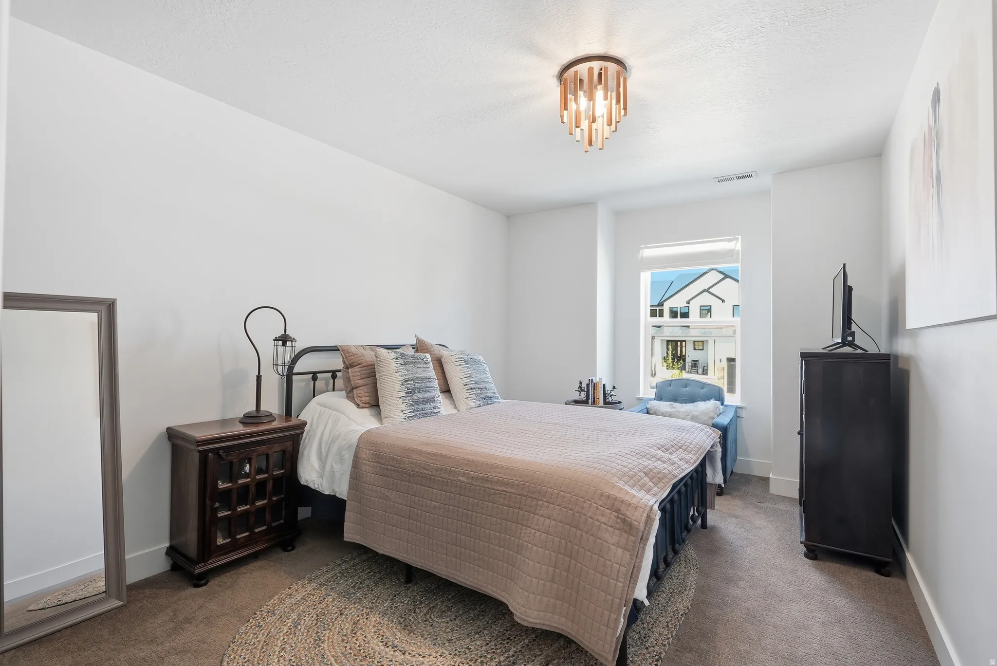 Bedroom featuring a window with natural light, a contemporary ceiling light fixture, neutral wall finishes, and carpeting