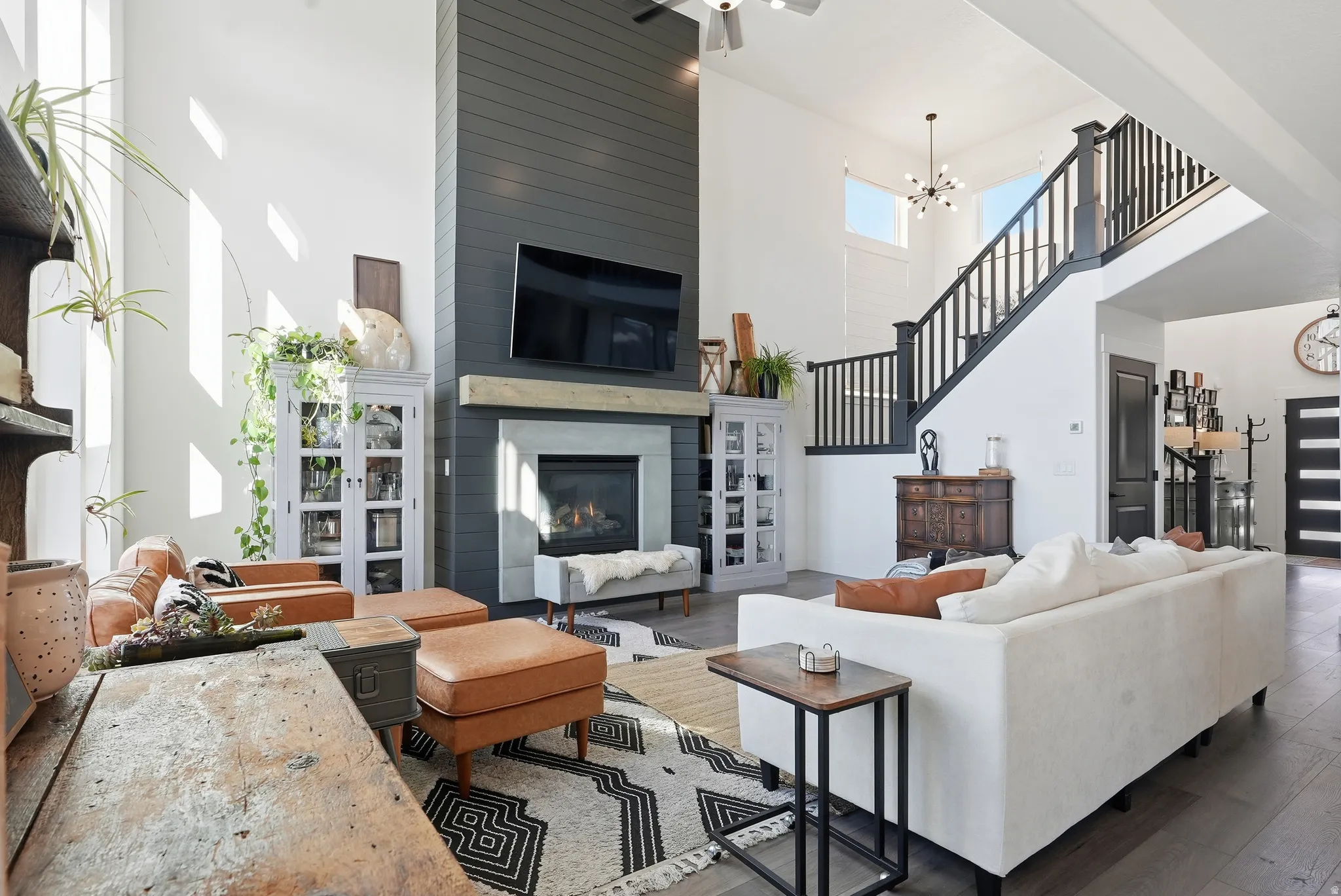 Spacious living area featuring high ceilings, a shiplap accent wall with a fireplace and mantel, and wood-finish flooring