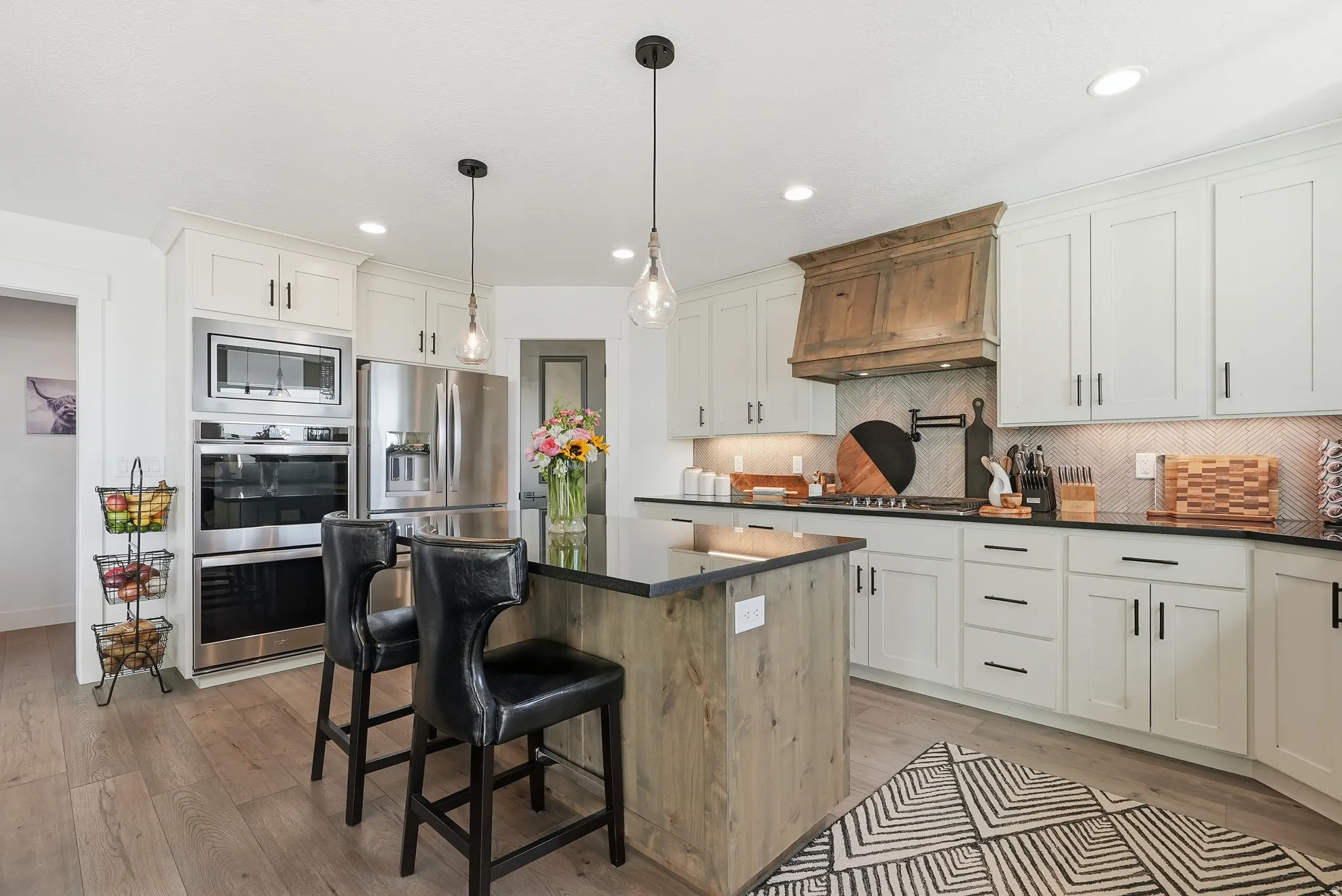 Spacious kitchen featuring an expansive island with a dark countertop and wood-finish base, complete with two pendant lights