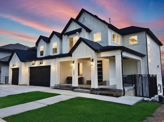 Modern farmhouse exterior featuring white board and batten siding with black trim, a multi-car garage with black doors, and a covered front porch