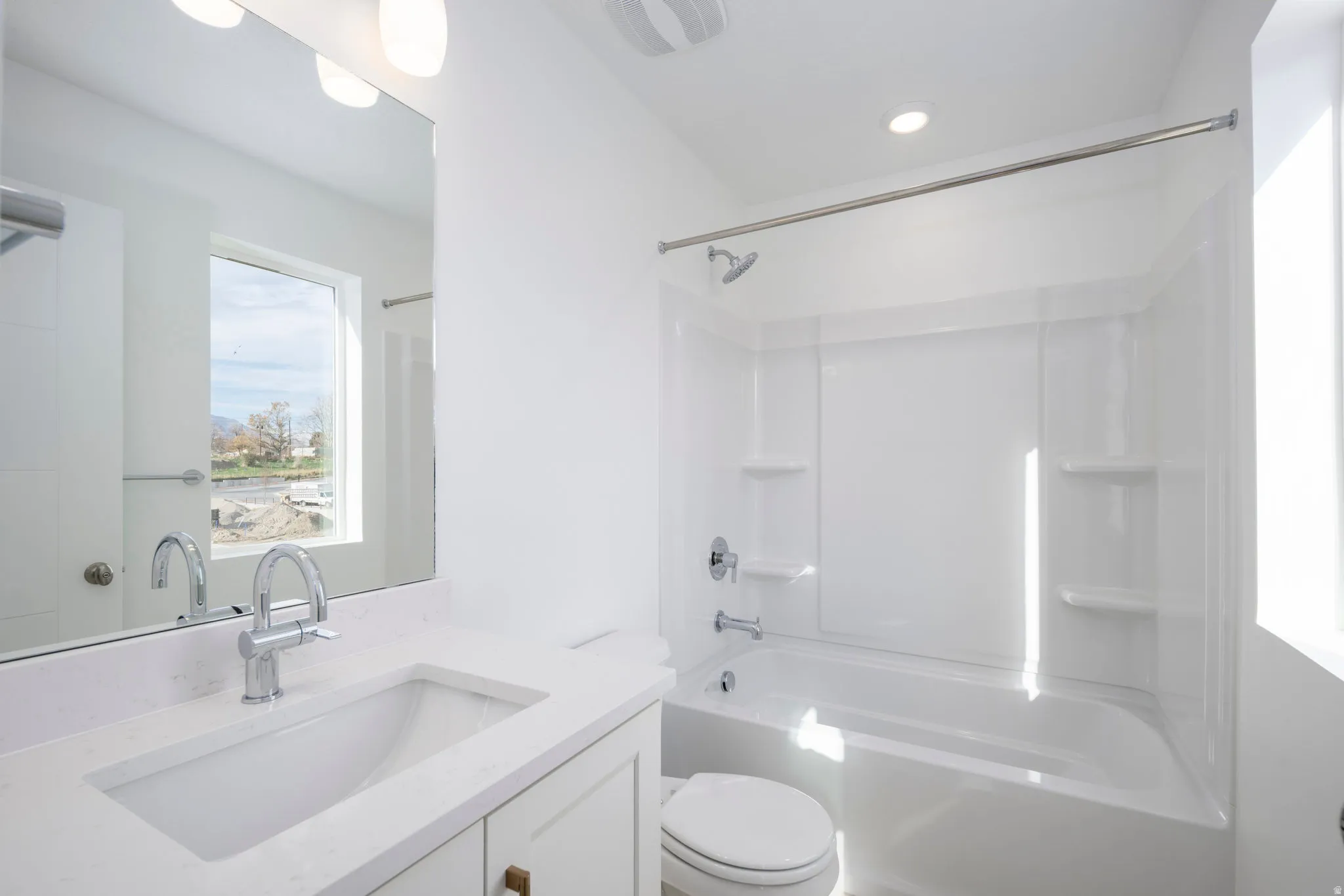 Bathroom featuring a white vanity with an integrated sink, polished chrome faucet, and rectangular mirror