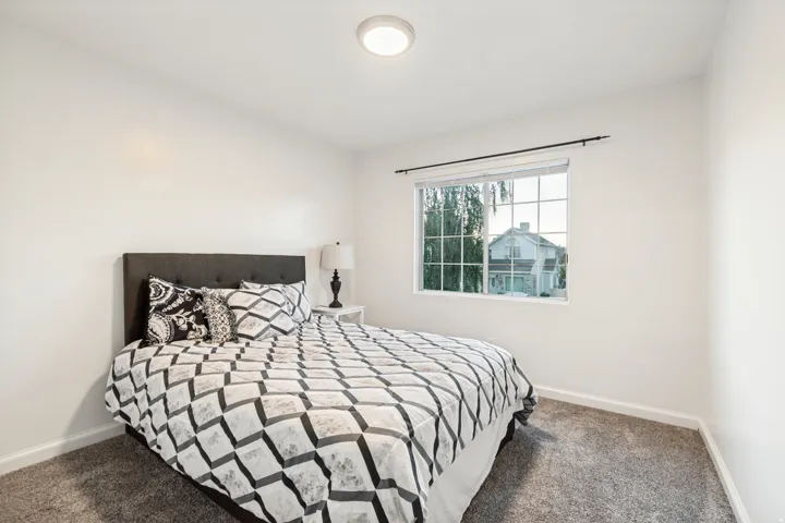 Bedroom featuring neutral wall paint, gray carpet flooring, a window with white blinds, and an overhead flush-mount light fixture