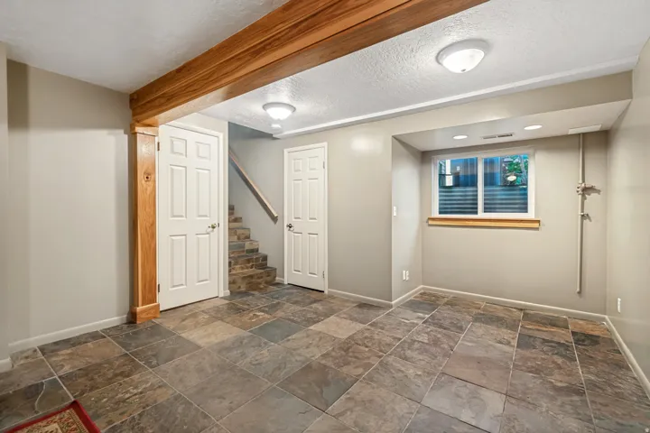 Spacious room featuring multi-toned slate tile flooring and a prominent wood beam detail