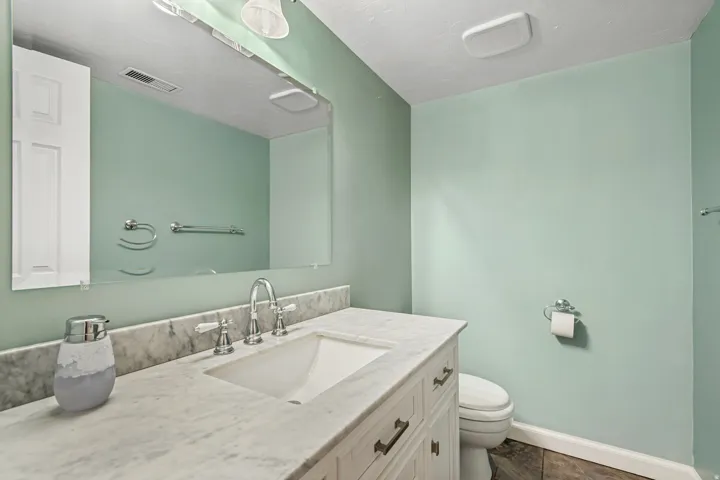 Bathroom featuring a vanity with a white countertop, an undermount sink, a polished chrome faucet, and a wall-mounted mirror