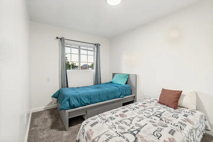 Room featuring neutral wall tones, grey textured carpet, a window with grey drapes, and a ceiling-mounted light fixture