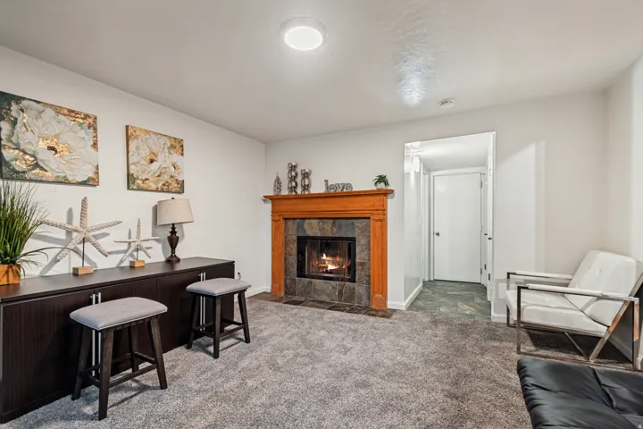 Living space featuring a natural wood fireplace mantel with stone surround, plush carpeting, and recessed lighting
