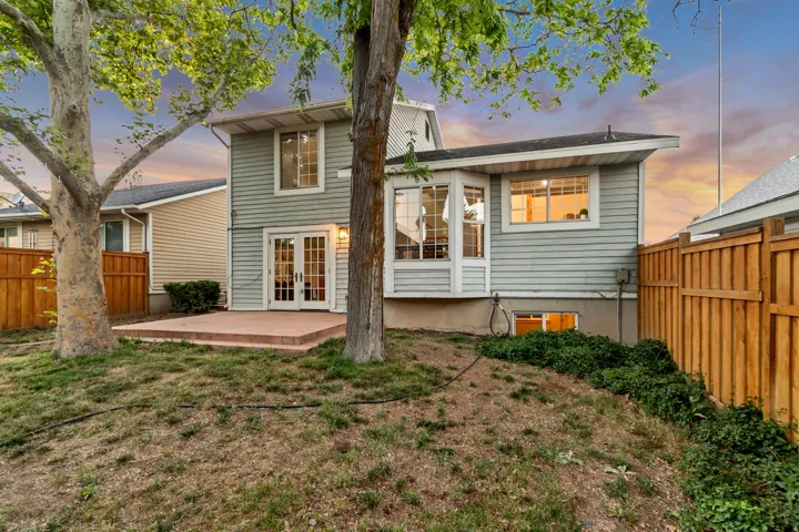Rear exterior featuring light blue siding, a ground-level patio, and French doors