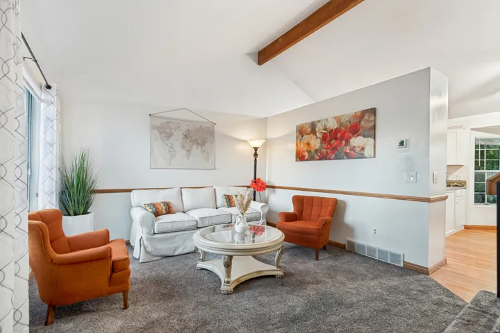 Living area featuring a vaulted ceiling with exposed wood beams