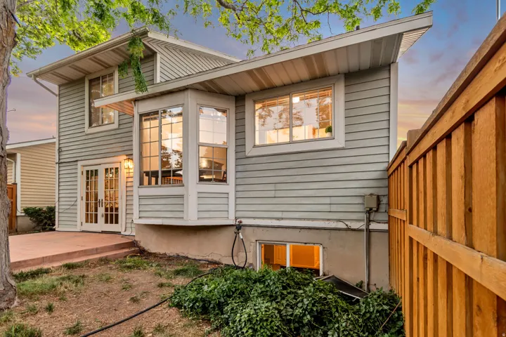Rear exterior featuring light blue siding, a bay window, and a patio with steps