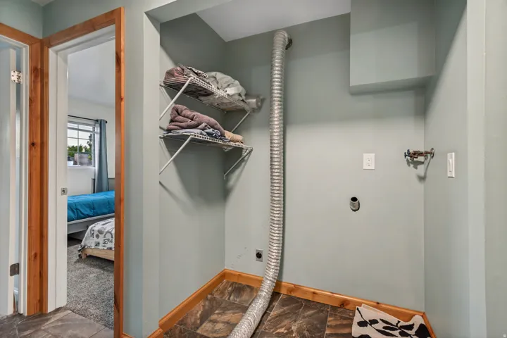 Dedicated utility space featuring hookups, tile-finish flooring, and built-in shelving