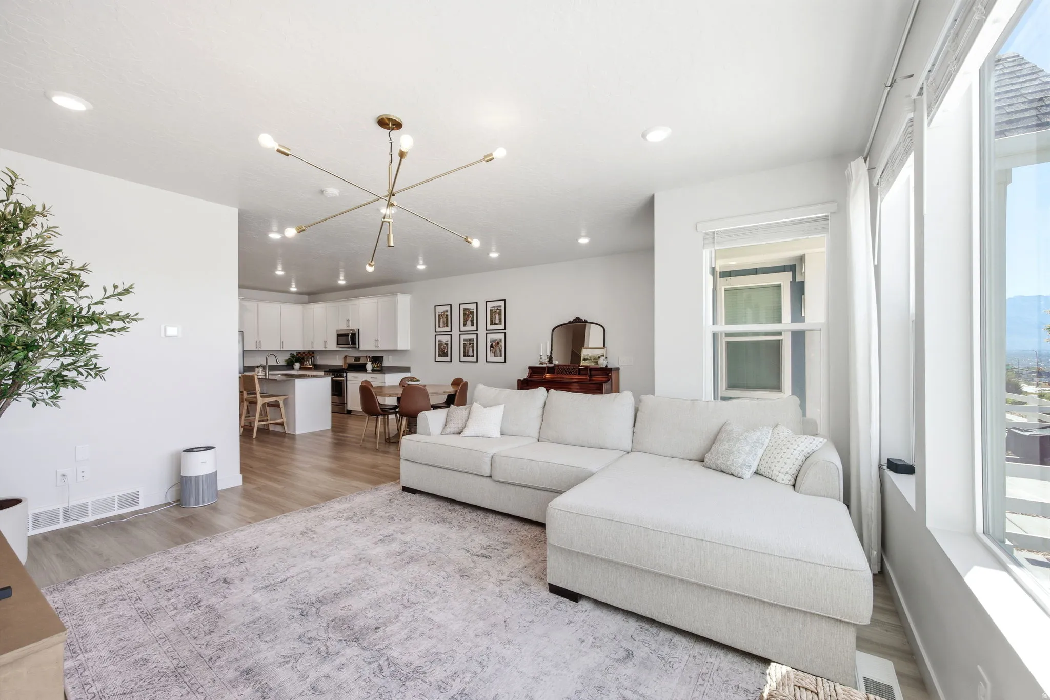 Spacious living area featuring light wood-finish flooring, a contemporary brass sputnik chandelier, and recessed lighting