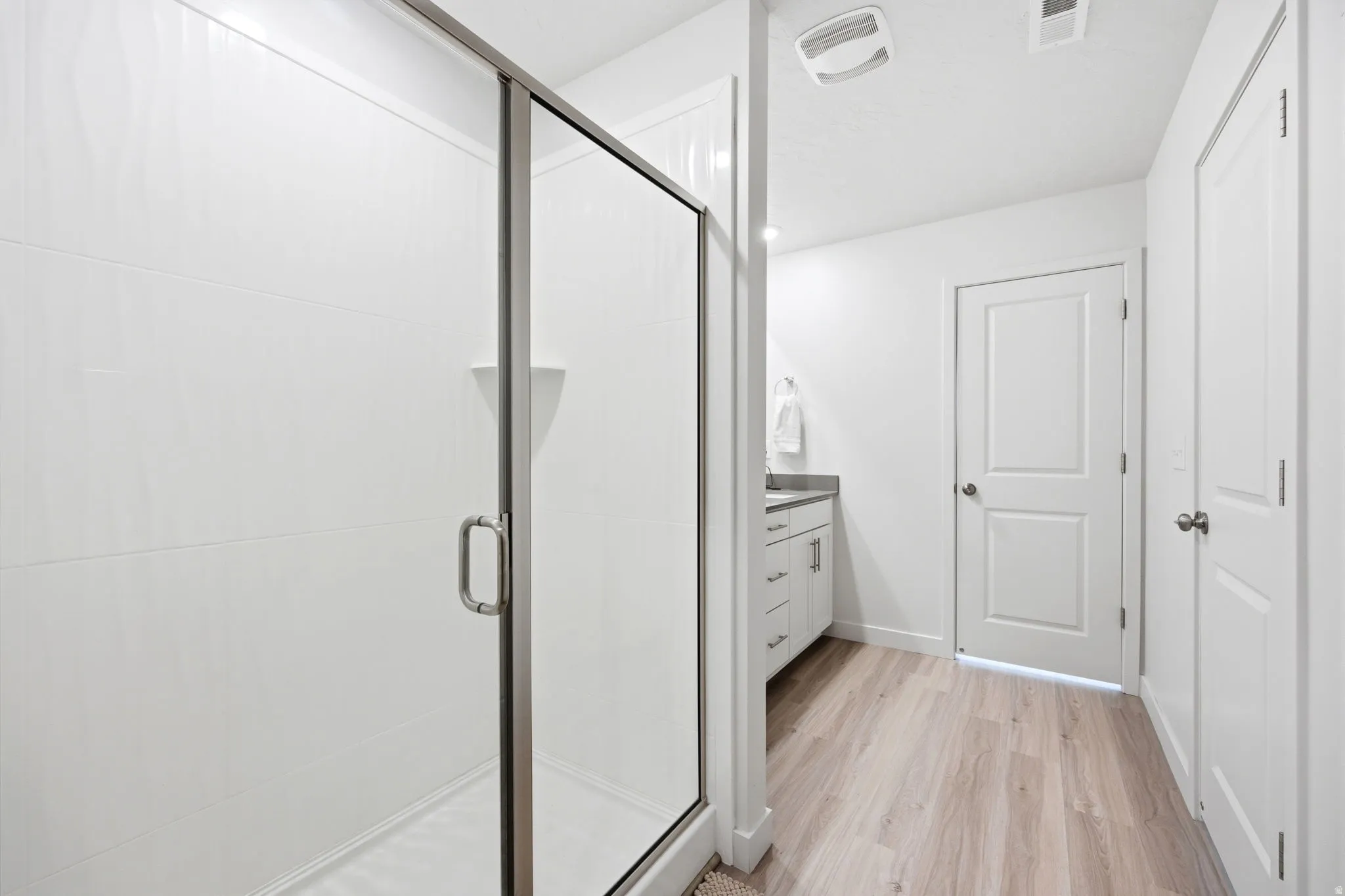 Walk-in shower with clear glass enclosure and white tile surround