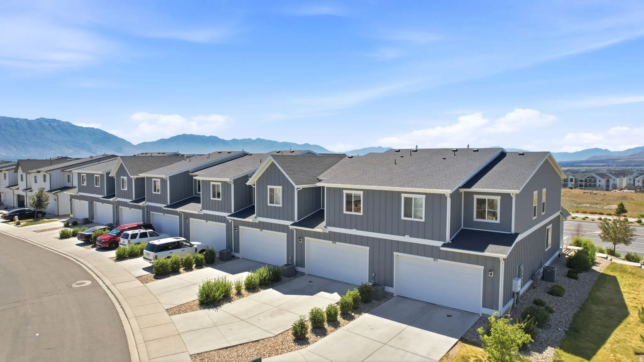 Row of gray two-story townhomes featuring white trim and individual garage doors