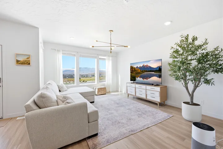 Spacious living area featuring light wood-finish flooring and ample natural light from multiple large windows