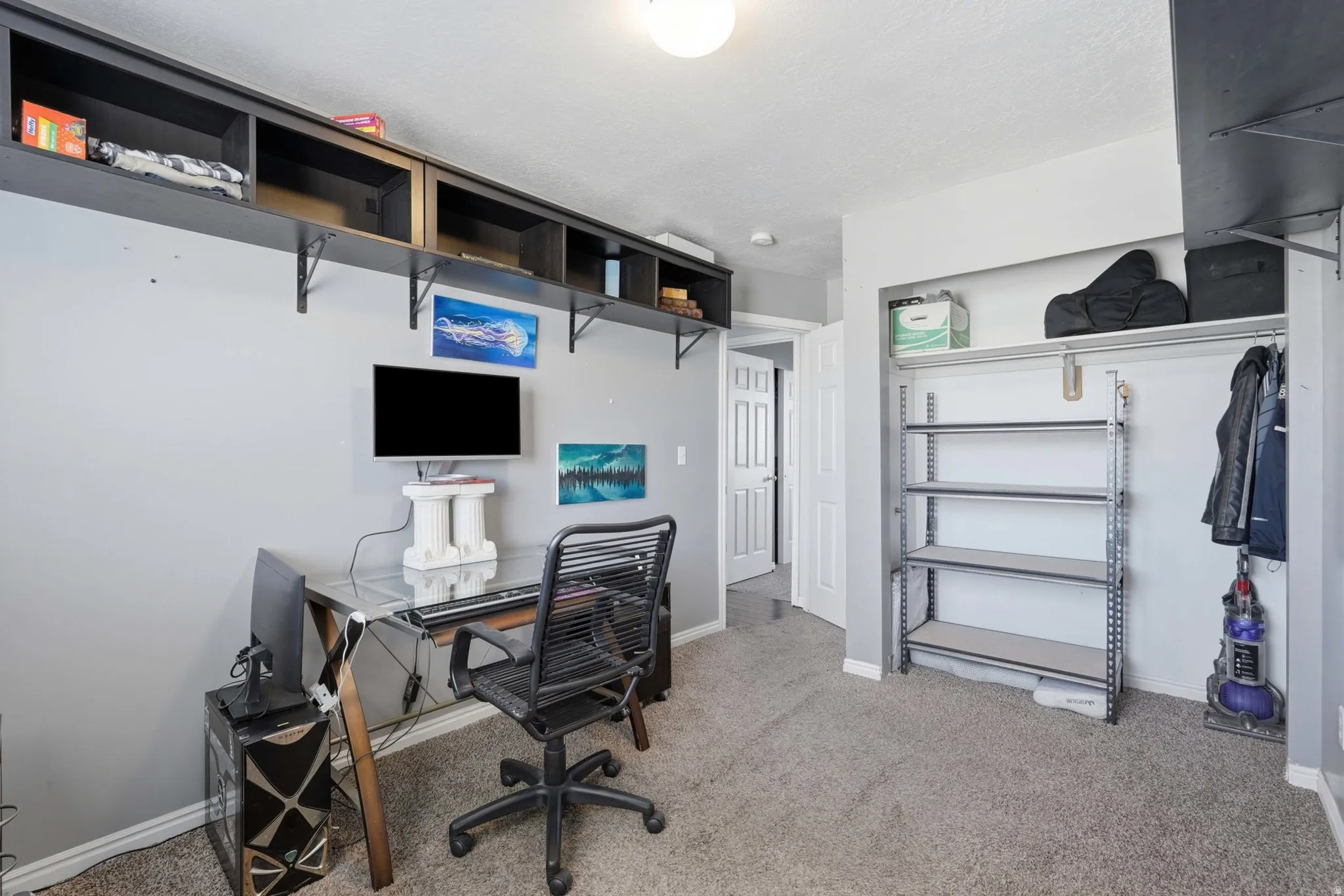 Interior room featuring a desk area with built-in shelving, carpet flooring, and a closet with shelving and hanging rod