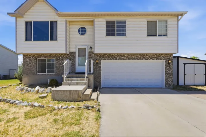 Split-level exterior featuring white siding and a stone facade