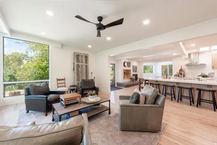 Light wood-finish flooring throughout, featuring recessed lighting and a modern ceiling fan