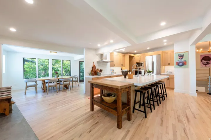 Open-concept kitchen and dining area featuring light wood-finish flooring, recessed lighting, and a large central island with seating