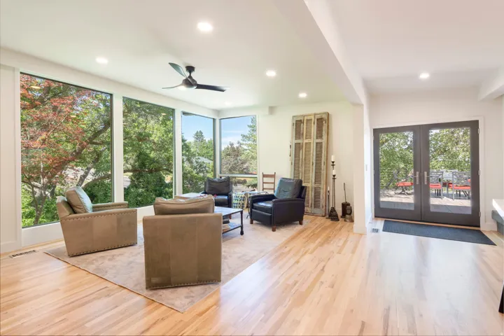 Living area with expansive floor-to-ceiling windows, light wood-finish flooring, recessed lighting, and a ceiling fan
