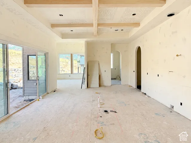 Vaulted ceiling with exposed wood beams, recessed lighting, and arched doorways