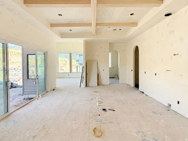 Vaulted ceiling with exposed wood beams, recessed lighting, and arched doorways