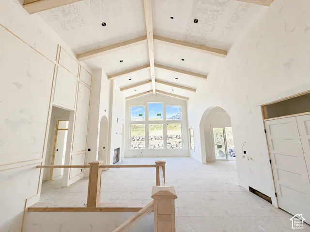 Vaulted ceilings with exposed wood beams, expansive windows, arched doorways, and custom wall paneling