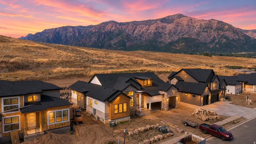 New construction homes featuring multi-tonal exteriors with natural stone accents, dark roofing, and multiple garage bays