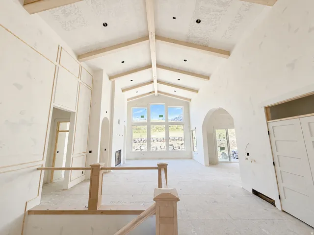 Vaulted ceilings with exposed wood beams, expansive windows, arched doorways, and custom wall paneling