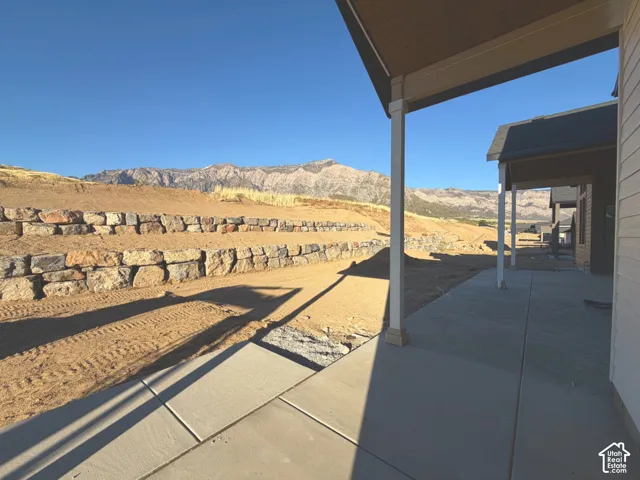 Covered patio with concrete surface, supporting columns, and mountain backdrop