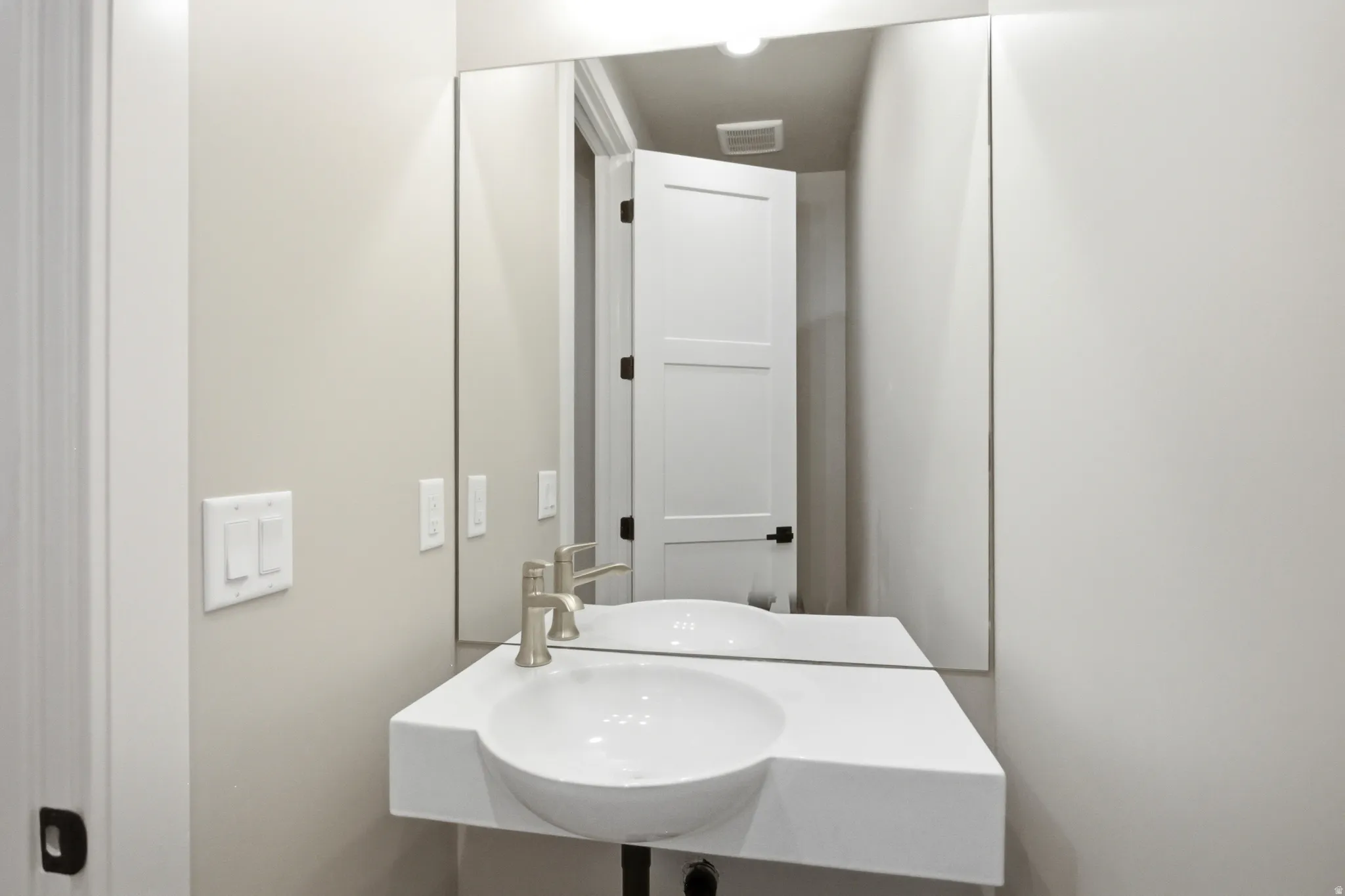 Modern half bathroom vanity featuring an integrated basin, brushed nickel faucet, and a large wall-mounted mirror