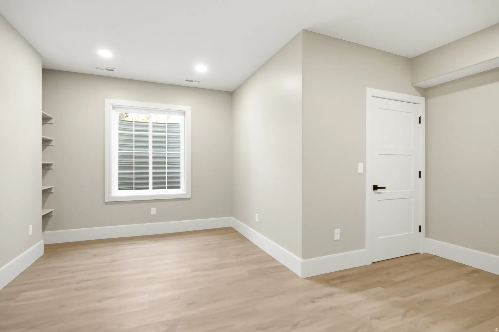 Bright room featuring wood-finish flooring, recessed lighting, and a white trim package