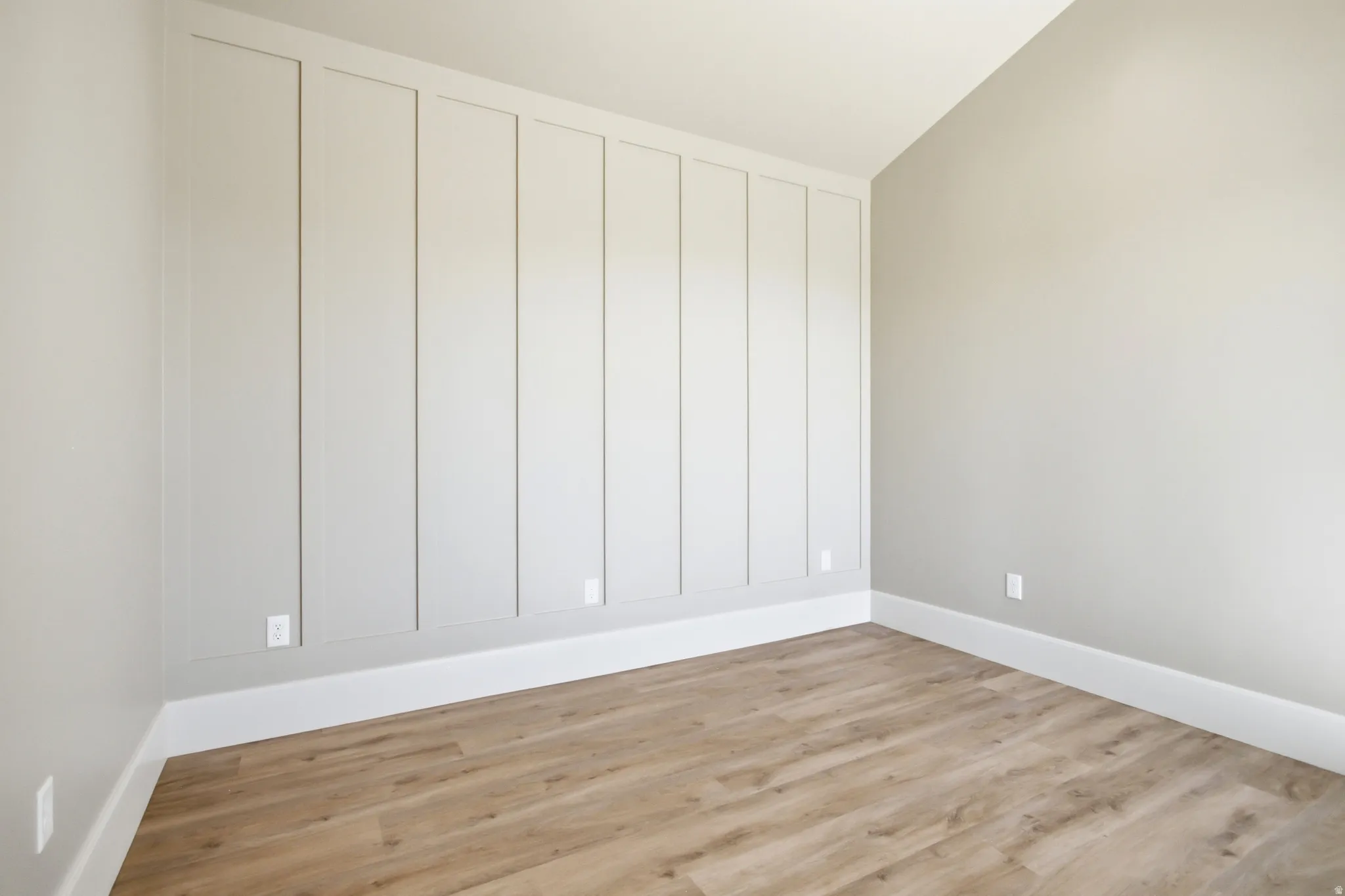 Accent wall featuring vertical paneling, crisp white baseboards, and neutral wall paint