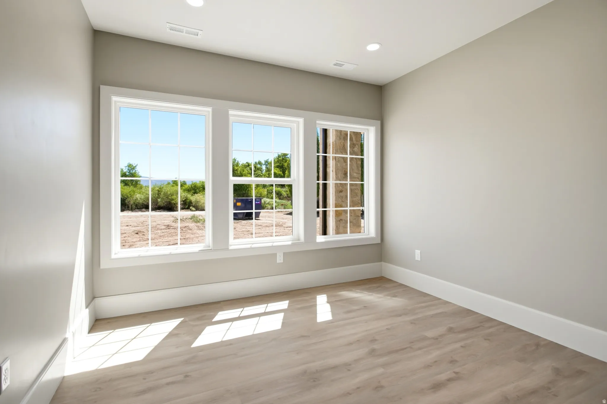 Bedroom featuring three large grid-pattern windows, recessed lighting, and neutral wall tones