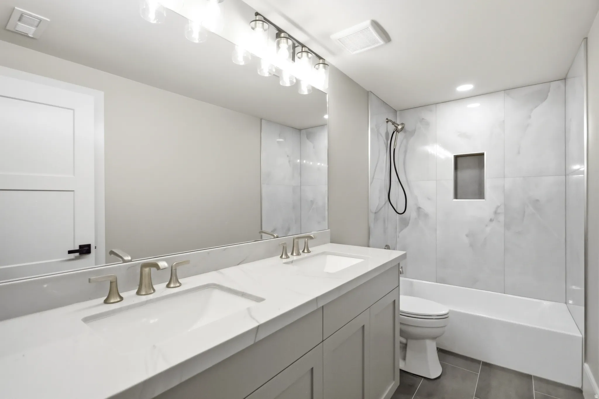 Bathroom featuring a dual-sink vanity with white countertops, brushed nickel faucets, and a full-width mirror