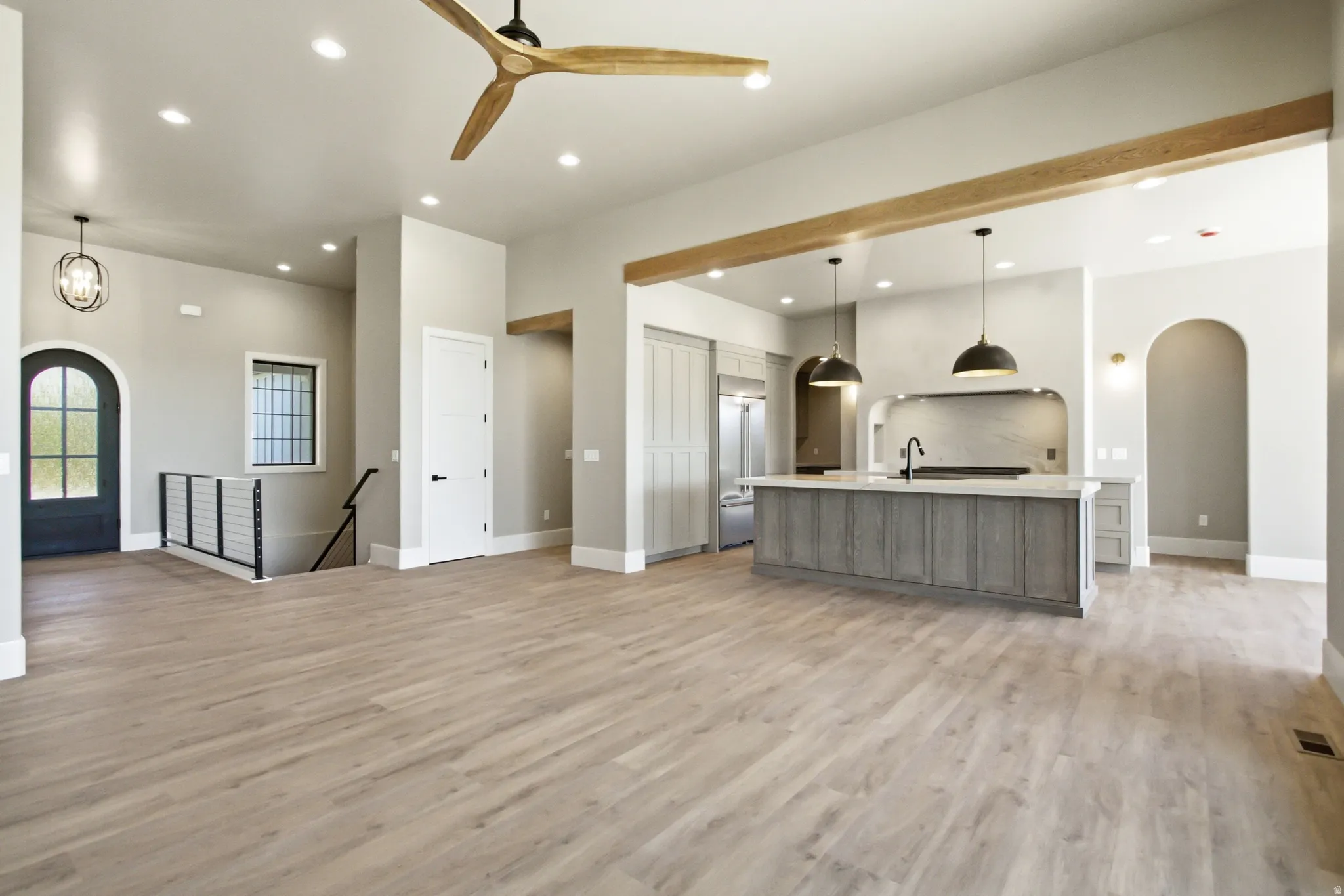Spacious interior featuring light wood-finish flooring, recessed lighting, and a prominent kitchen island with a dark countertop and pendant lighting