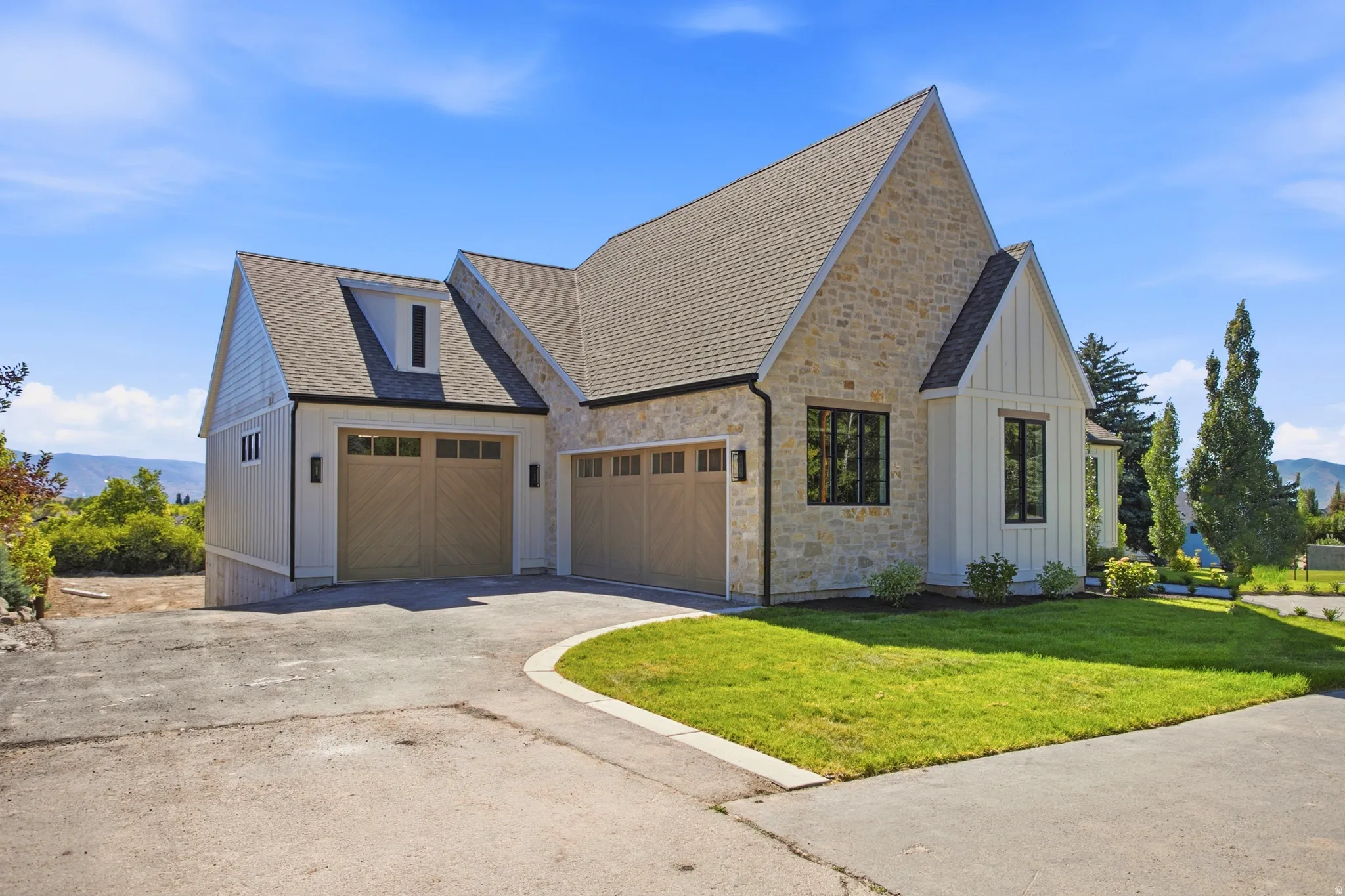Modern farmhouse exterior featuring stone and vertical panel siding, a multi-gabled roofline, and integrated Three-car garage with wood-finish doors
