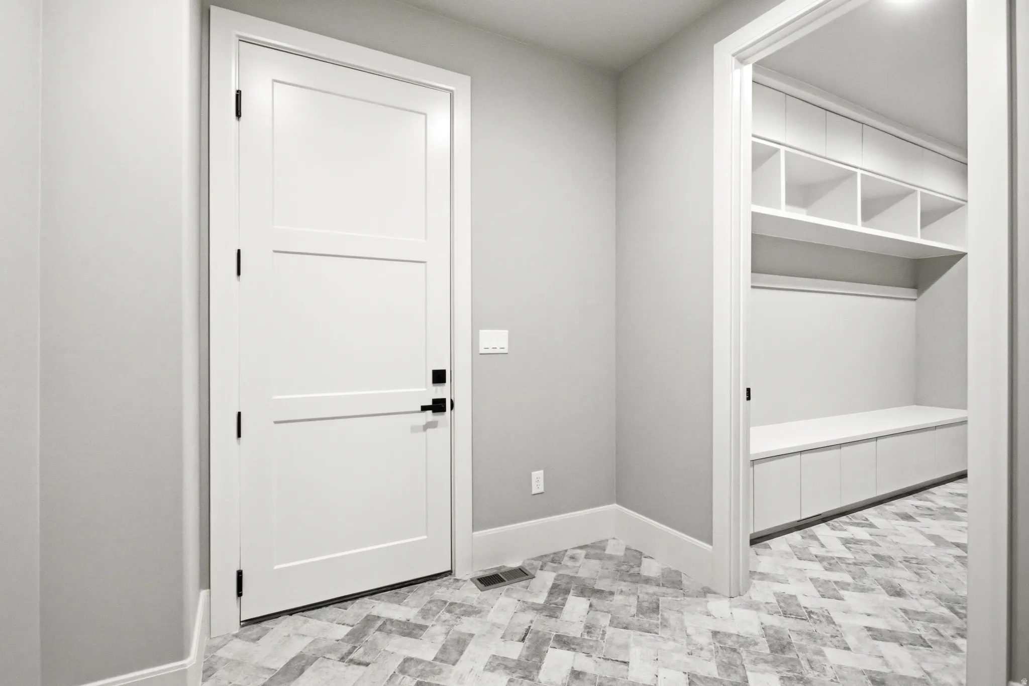 Dedicated mudroom space featuring built-in cabinetry, open shelving, and a bench with integrated storage