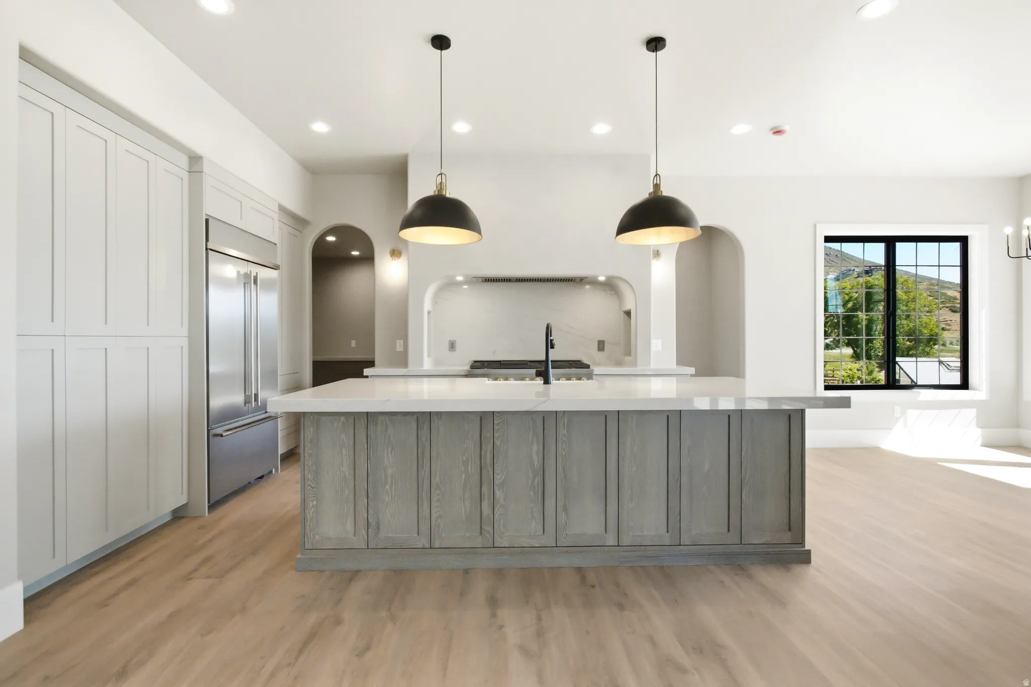 Open-concept kitchen featuring an oversized island with light-toned wood-finish cabinetry and a light-toned countertop