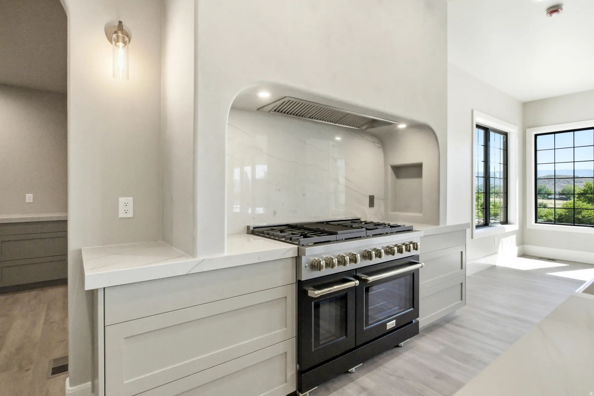 Professional-grade range with stainless steel hardware, set within an arched alcove with a tile backsplash