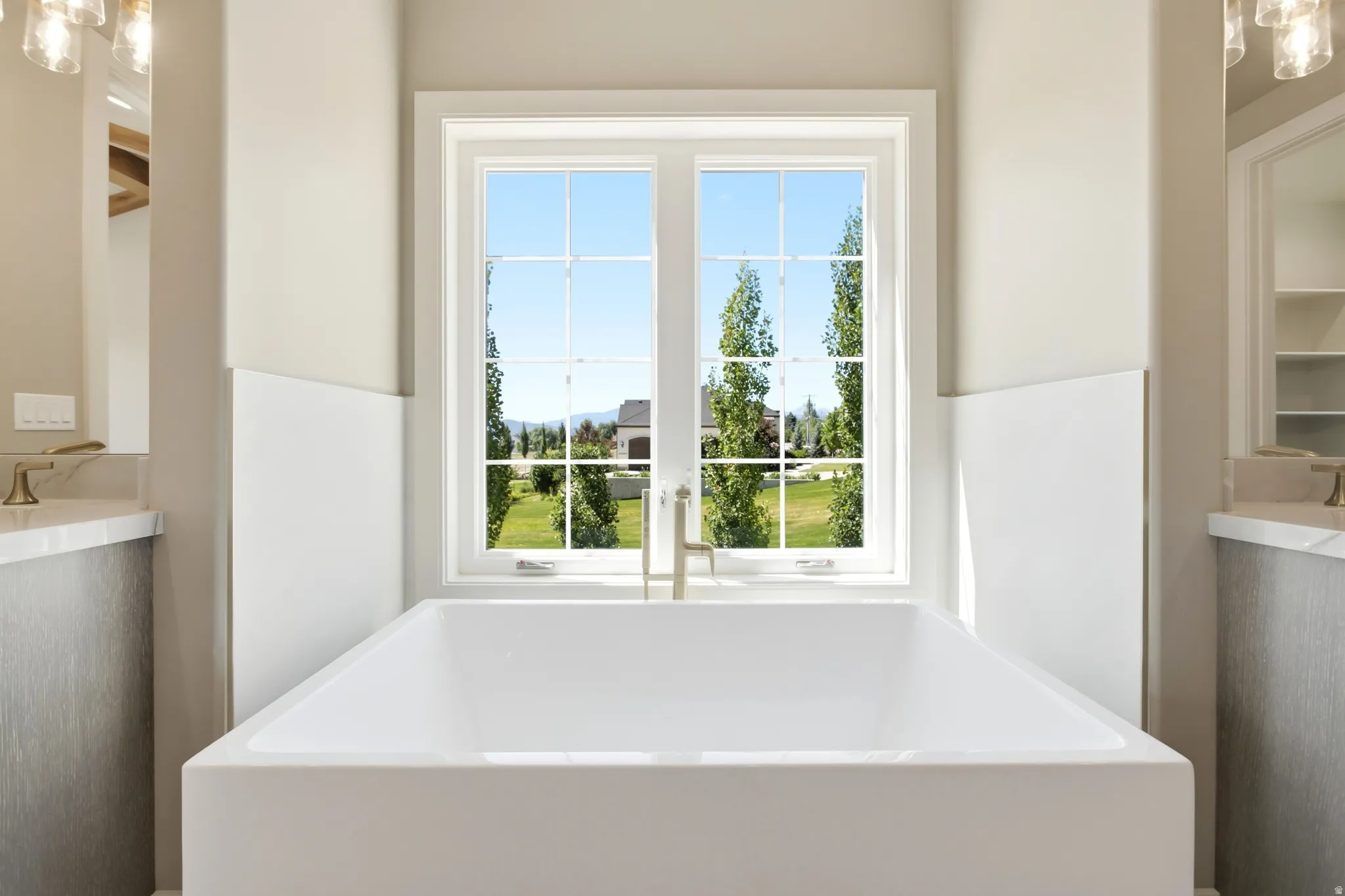 Freestanding soaking tub centered beneath a multi-pane window