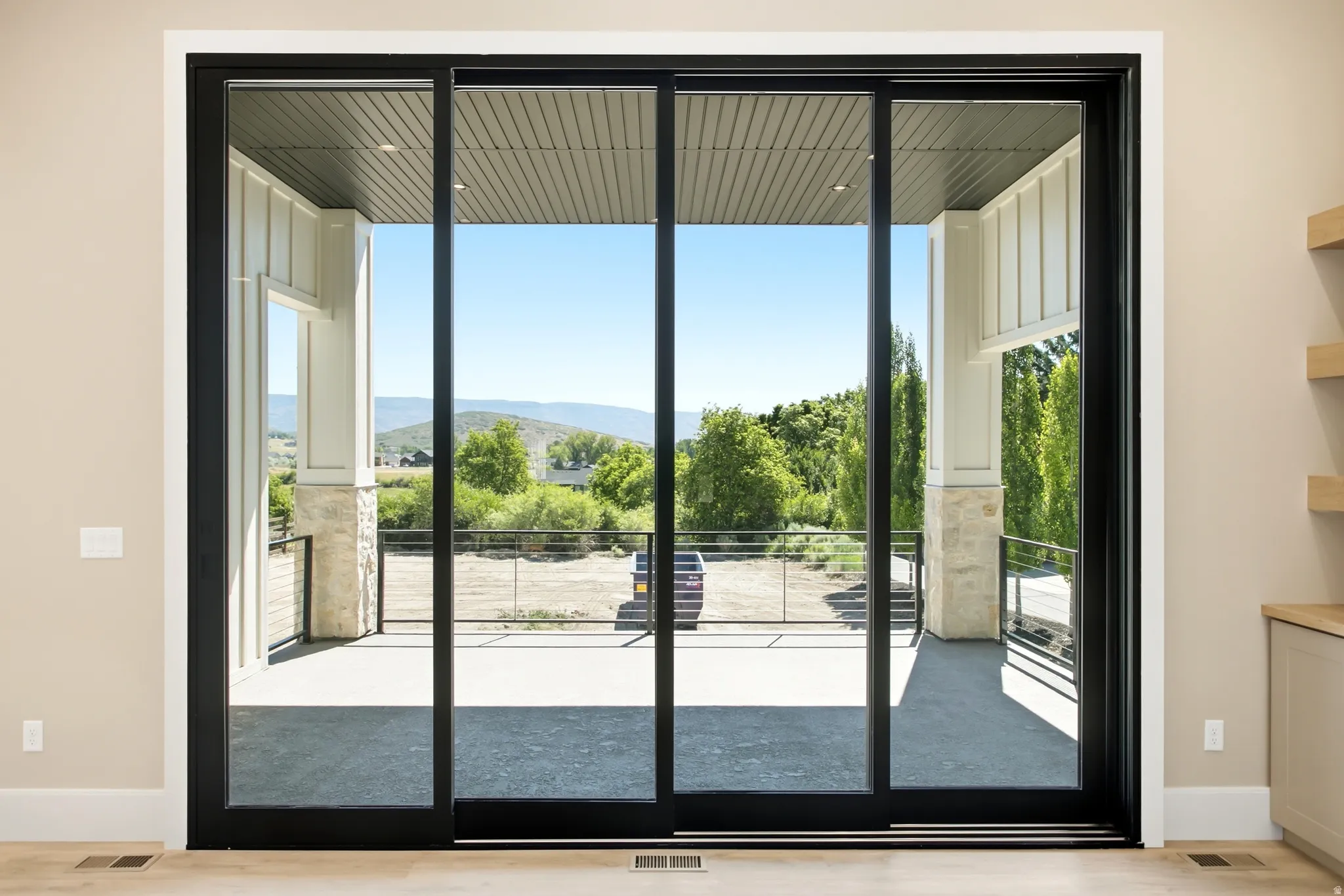 Expansive sliding glass doors with black frames open to an outdoor patio