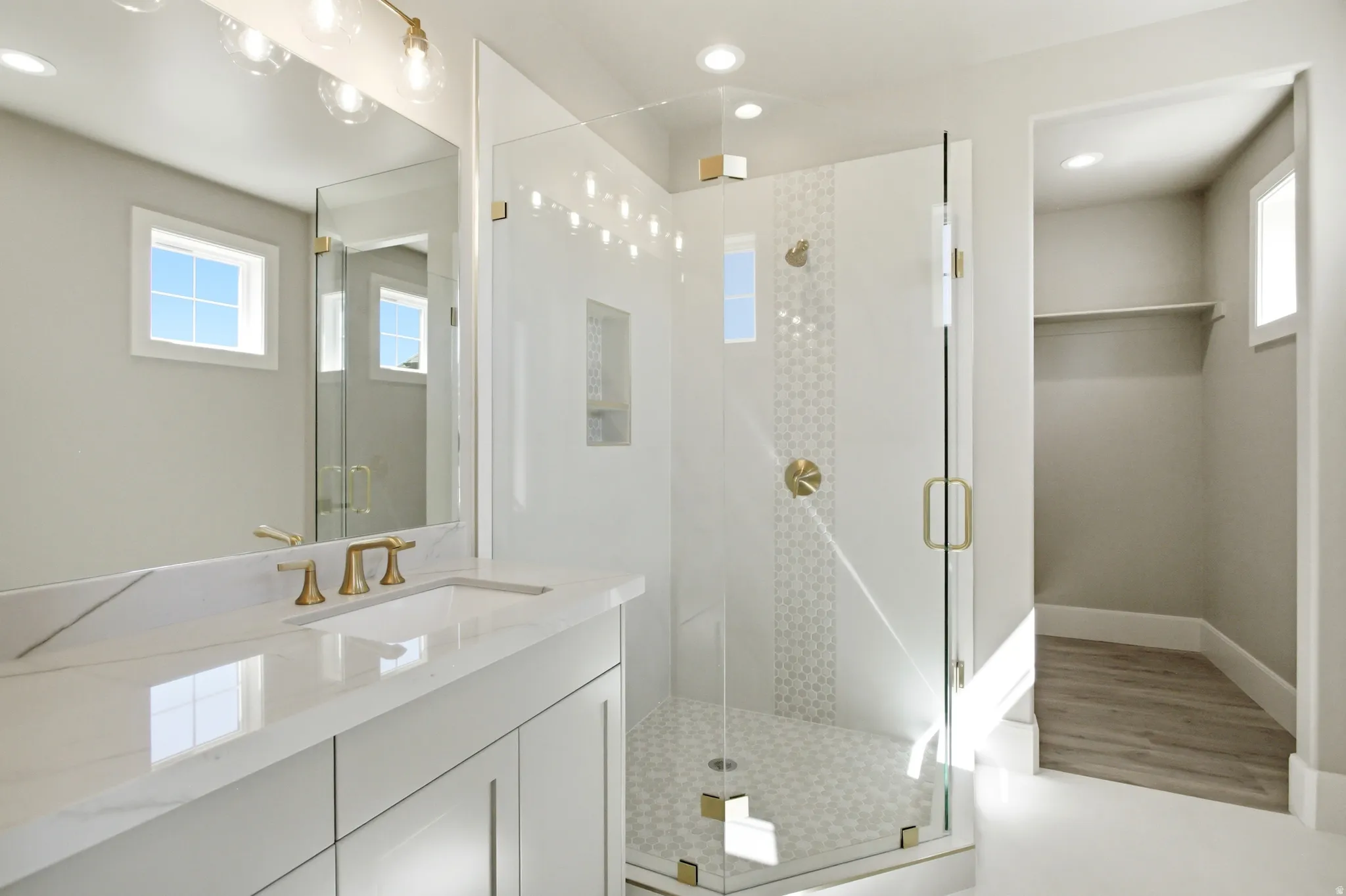 Modern bathroom featuring a single vanity with stone-finish countertop, undermount sink, and brass-finish faucet