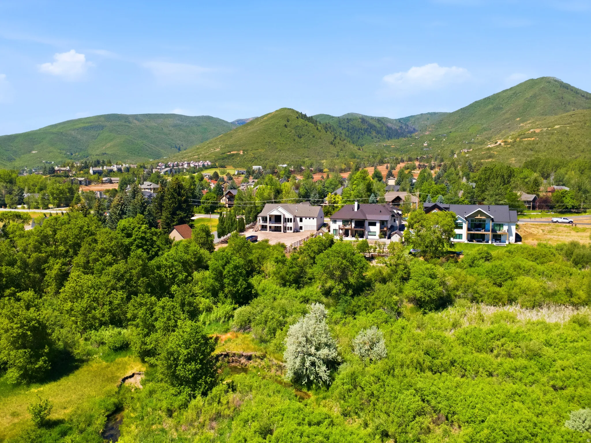 Lush green landscape  and back of home featuring a natural waterway and distant mountain ranges
